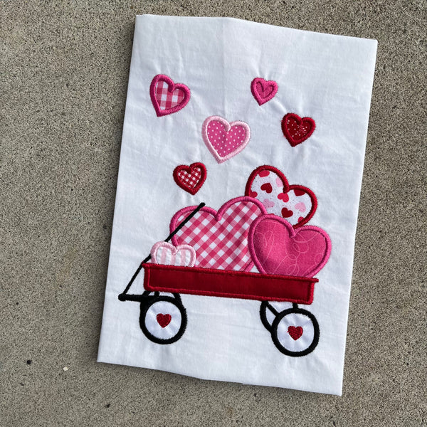 An applique of a wagon full of hearts by snugglepuppyapplique.com