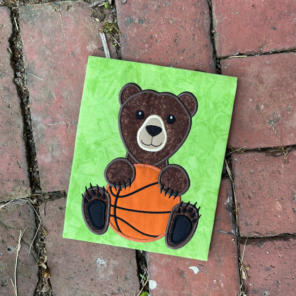 An applique of a bear holding a basketball by snugglepuppyapplique.com