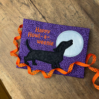 an applique of a dachshund howling at the moon and the words "Happy Howl-a-weenie" by snugglepuppyapplique.com