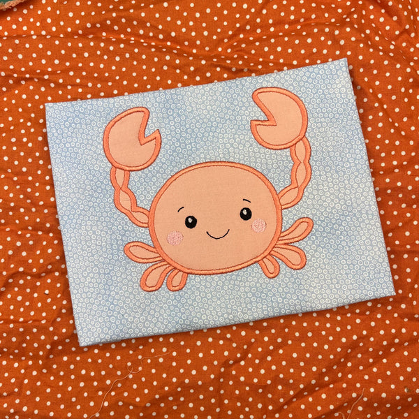 An appliqué of a babyish looking crab by snugglepuppqappliqe.com