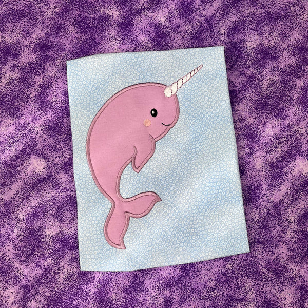 An applique of a babyish looking Narwhale by snugglepuppyapplique.com