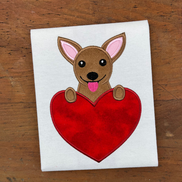 A Valentine applique of a chihuahua with its paws on a heart shape by snugglepuppyapplique.com