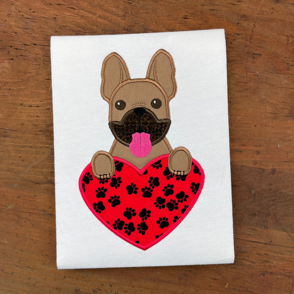 An applique of a French bulldog with its paws on a heart shape by snugglepuppyapplique.com