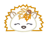 An applique of a sleeping hedgehog with fall leaves and an acorn by snugglepuppyapplique.com  Edit alt text